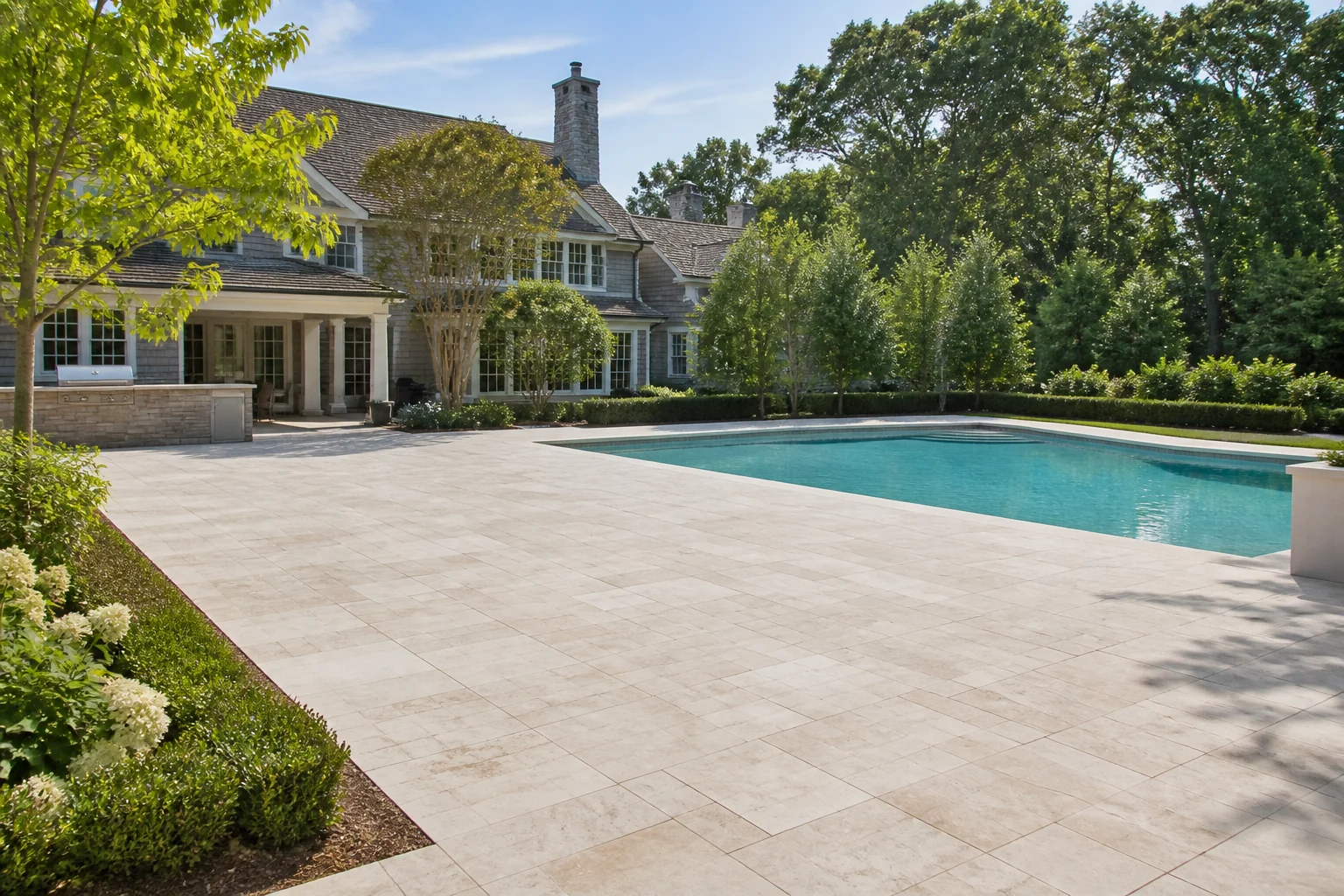 Spacious residential backyard with an open stone patio beside a swimming pool