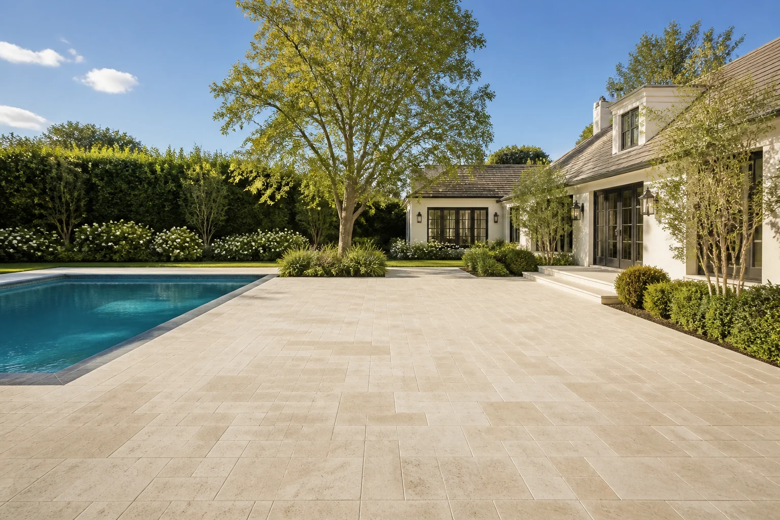 Elegant landscaped backyard pool with a broad open stone patio